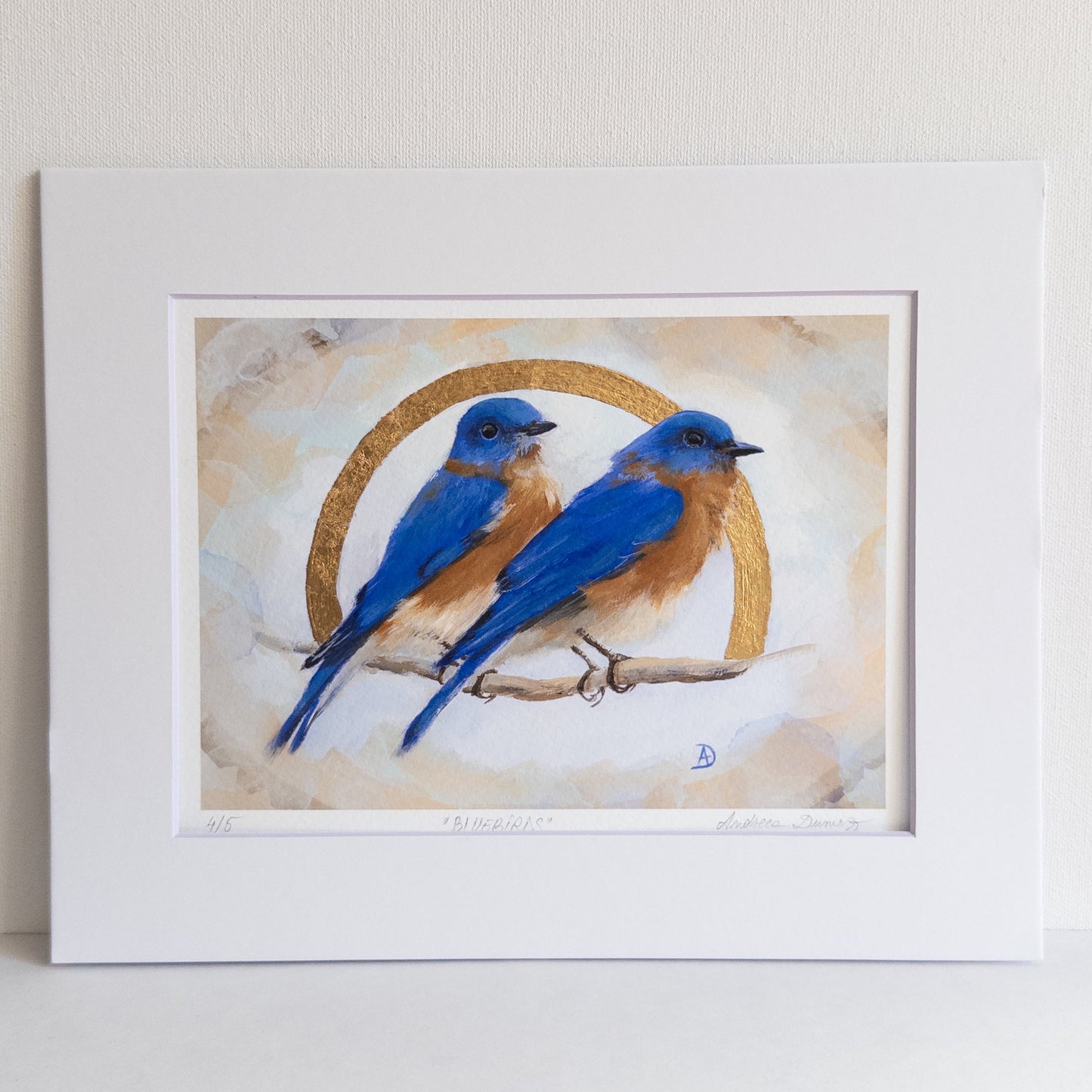 Framed artwork of two blue birds on a branch with a circular design in the background.